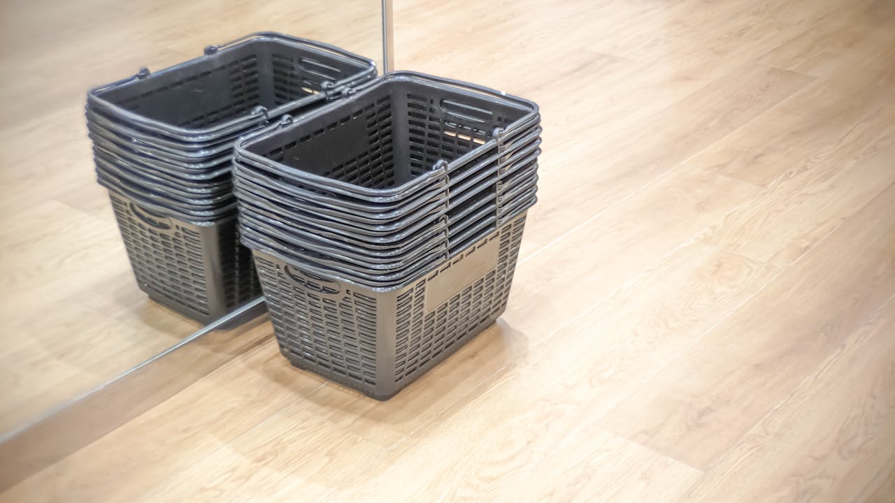 why-choose-us A stack of empty shopping baskets reflected in a mirror on a wooden floor.